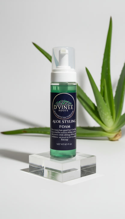 Bottle of D'Vinee Roots Aloe Styling Foam on a clear stand with aloe vera plant leaves in the background.