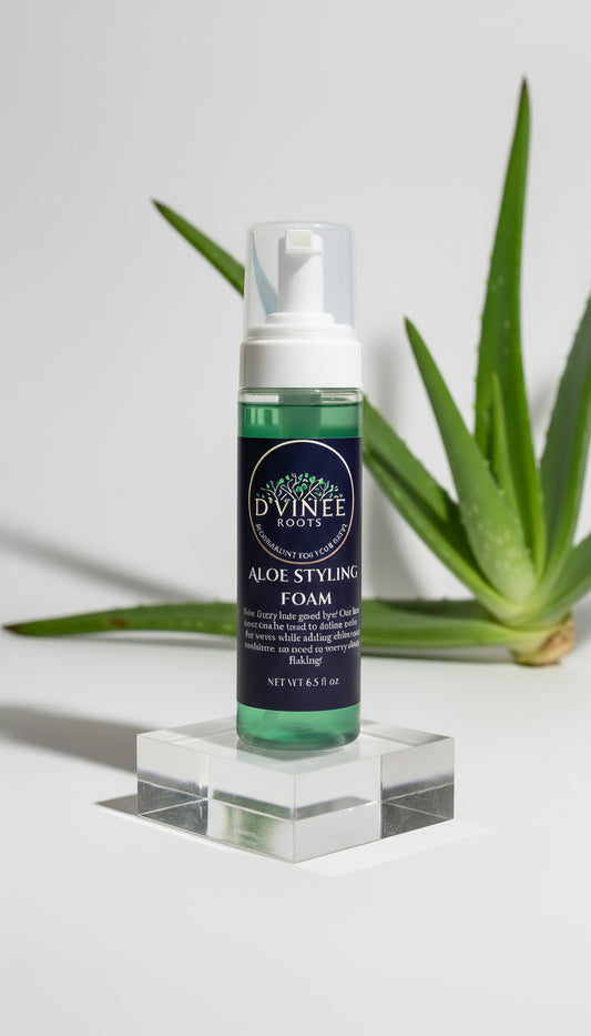 Bottle of D'Vinee Roots Aloe Styling Foam on a clear stand with aloe vera plant leaves in the background.